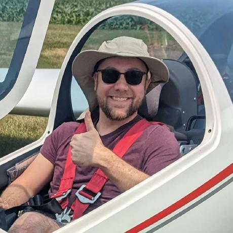 Photo of Andy Korth wearing a hat and sunglasses, sitting in a small glider airplane. Andy Korth